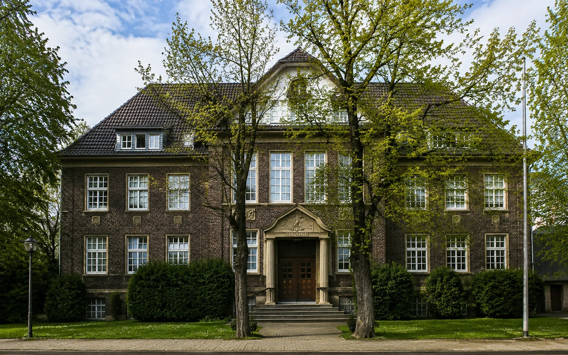 Altes Rathaus Voerde Historisches Backsteingebäude des alten Rathauses Voerde mit Eingangsportal, großen Fenstern und Bäumen vor der Fassade